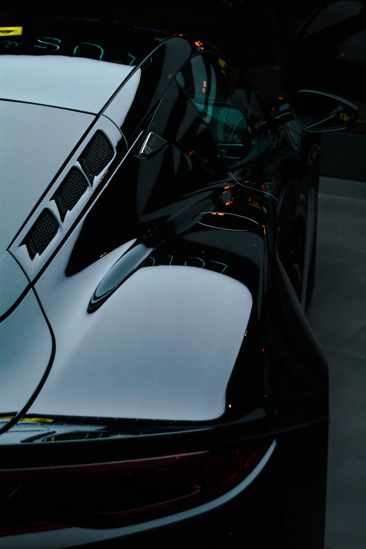 Reflections across the glossy black body of a sports car