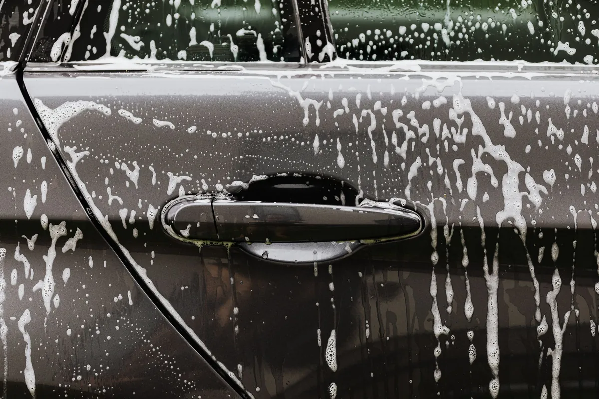 Wash foam running down the door of a dark car