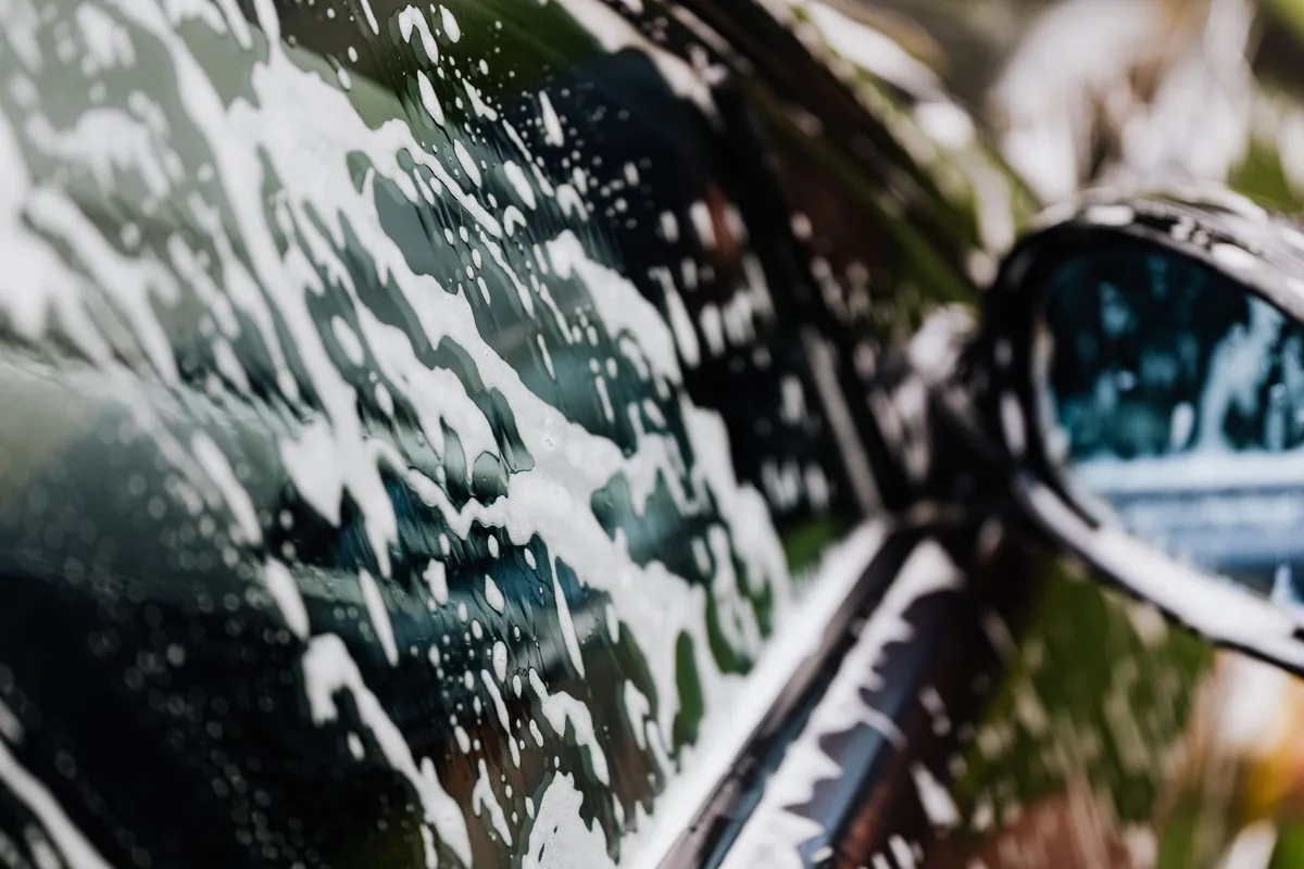 Foam sliding off a car window beside the mirror