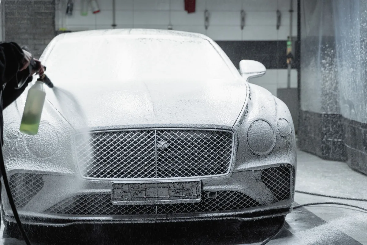 A luxury car covered nose to tail in wash foam