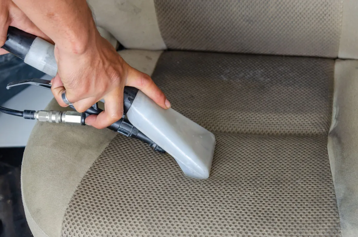 An extractor nozzle lifting dirt out of a cloth car seat