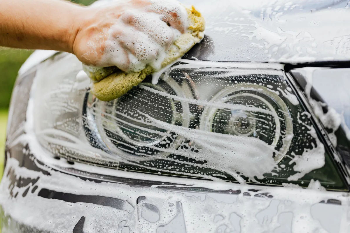 A soapy wash mitt on a car's headlight